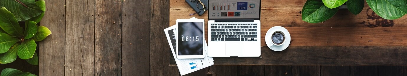 image d'un bureau en bois avec une tasse de café, un ordinateur portable et une tablette